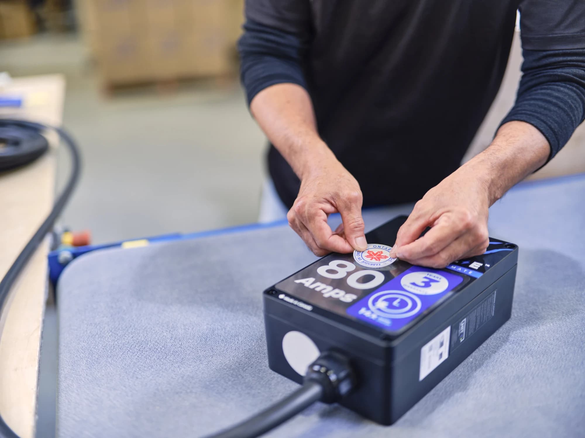 Technician applying a Made in Ontario label to a Grizzl-E Ultimate 80A charger