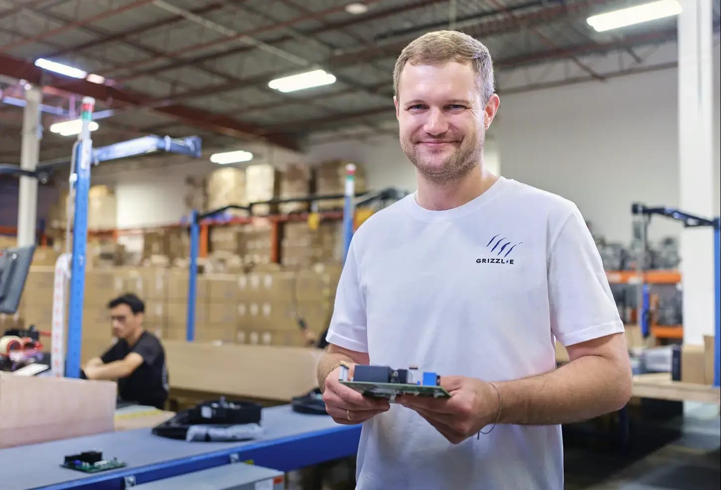 A Grizzl-E technician holding a charger circuit board on the assembly line in Ontario